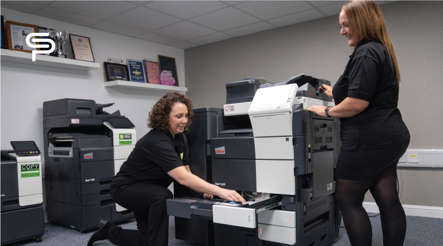 Two Copy Print Services team members working on multifunction photocopiers in the showroom