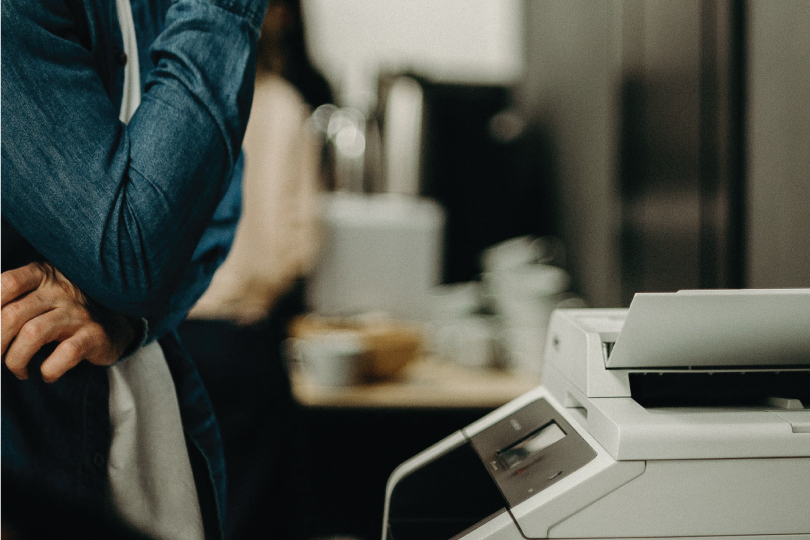 Office worker standing beside a multifunction photocopier